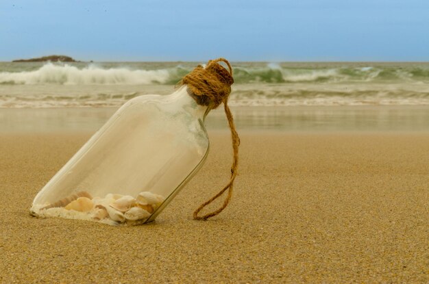 Flasche am Strand voller Muscheln und Sand