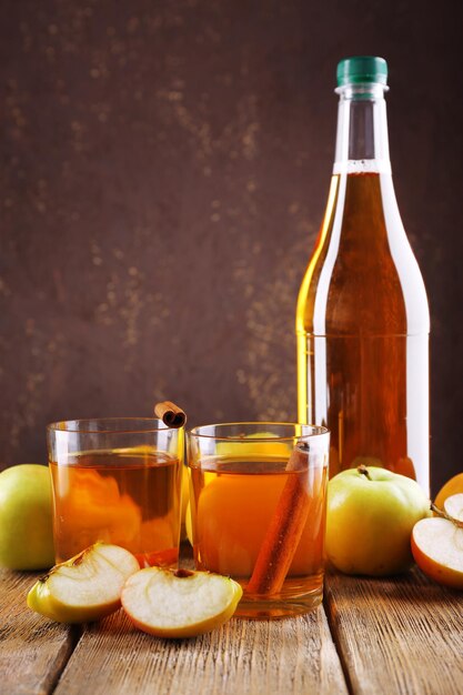 Flasche Apfelessig mit frischen Äpfeln auf Holztisch