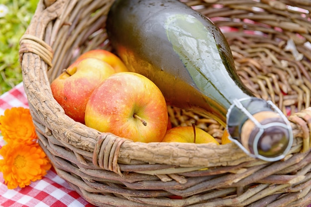 Flasche Apfelwein mit Äpfeln in einem Korb