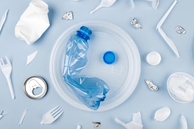 Flasche auf dem Teller und anderer Plastikmüll auf blauem Hintergrund