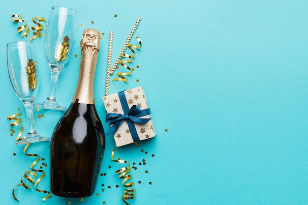 Flasche Champagner mit farbigem Glitzerkonfetti und Geschenkbox Platz für Text auf farbenfrohem Hintergrund Draufsicht Urkomische Weihnachts- und Geburtstagsfeier