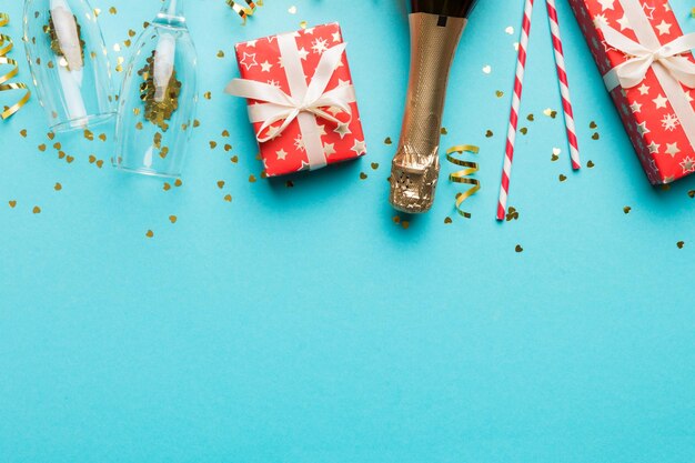 Flasche Champagner mit farbigem Glitzerkonfetti und Geschenkbox Platz für Text auf farbenfrohem Hintergrund Draufsicht Urkomische Weihnachts- und Geburtstagsfeier