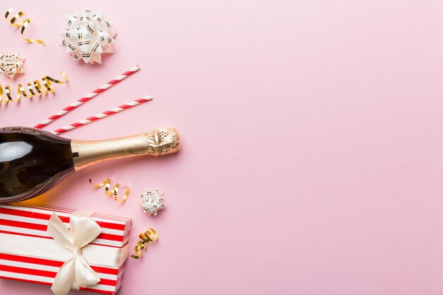 Flasche Champagner mit farbigem Glitzerkonfetti und Geschenkbox Platz für Text auf farbenfrohem Hintergrund Draufsicht Urkomische Weihnachts- und Geburtstagsfeier