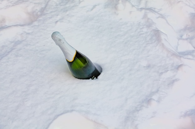 Flasche Champagner ragt aus Schnee für Feierparty Sonniger Wintertag