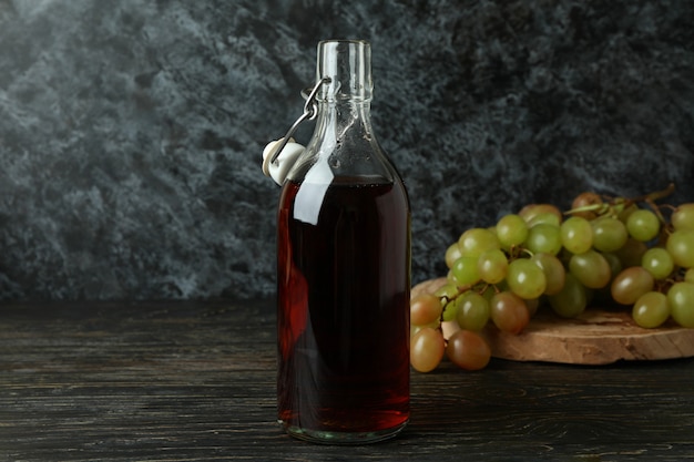 Foto flasche essig und traube auf rustikalem holztisch