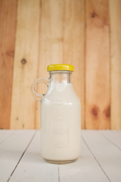 Flasche Glas Milch auf einem Holztisch.