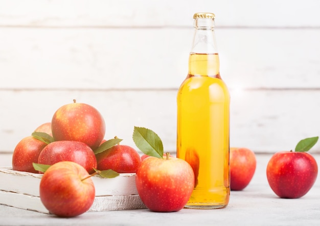 Flasche hausgemachter Bio-Apfelwein mit frischen Äpfeln in Schachtel auf Holzhintergrund Glas mit Eiswürfeln