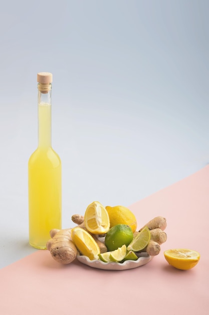 Flasche hausgemachter Saft mit Ingwer und Zitrone auf blauem und rosafarbenem Hintergrund Vertikal