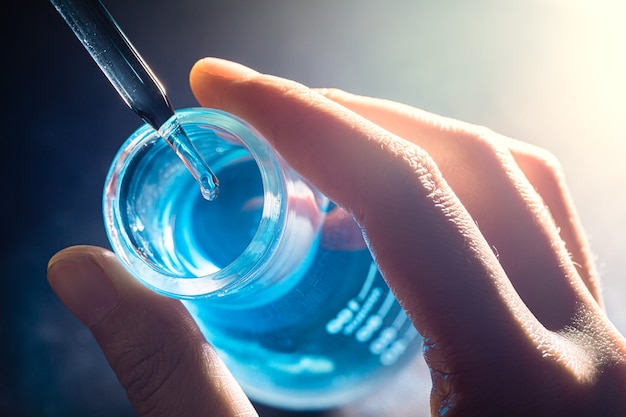 Flasche in der Hand des Wissenschaftlers mit Laborglashintergrund in der Laborwissenschaft