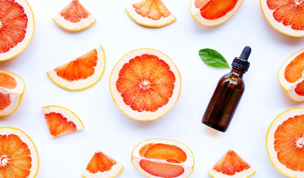 Flasche mit ätherischen Ölen mit Grapefruitscheiben auf weißem Hintergrund.