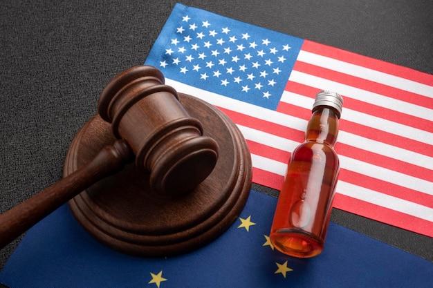 Flasche mit Alkohol und hölzernem Richterhammer auf USA- und EU-Flaggen Konzept der Alkoholklage in den Vereinigten Staaten von Amerika und der Europäischen Union Alkoholsteuer