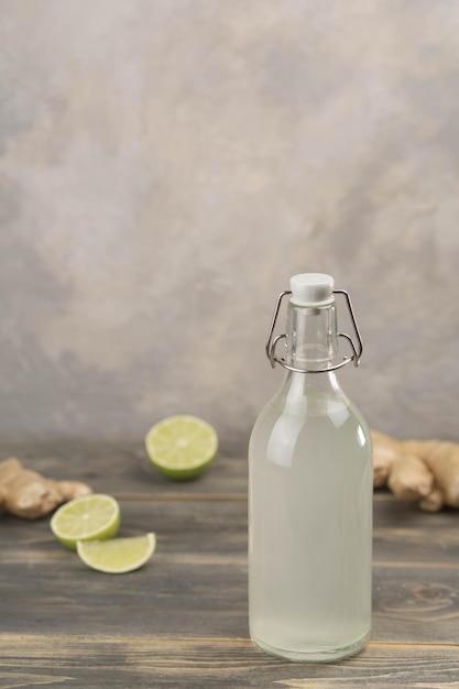 Flasche mit hausgemachter Ginger Ale Zitrone und Gingerroot auf grauem Hintergrund