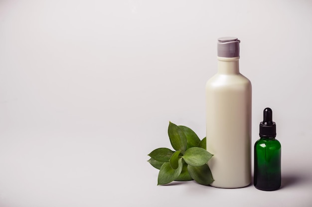 Flasche mit kosmetischem Produkt, ätherischem Öl und grünem Zweig. Konzept der natürlichen Ökologie. Getönt.