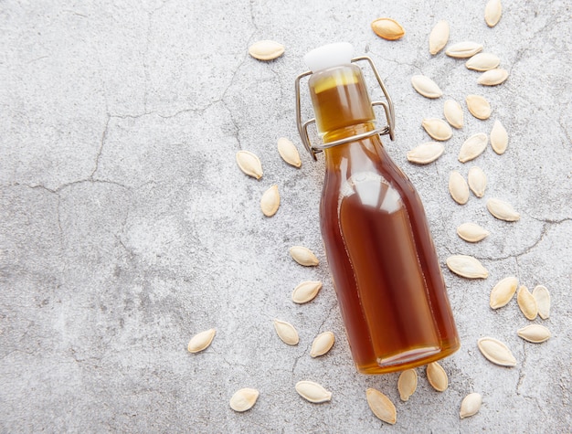 Flasche mit Kürbiskernöl auf grauem Betonhintergrund