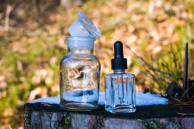 Flasche Parfüm auf einem Holzbrett, Glasstücke im Gras