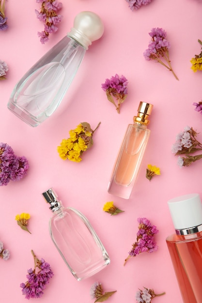 Flasche Parfüm mit Blumen auf rosa Tisch.