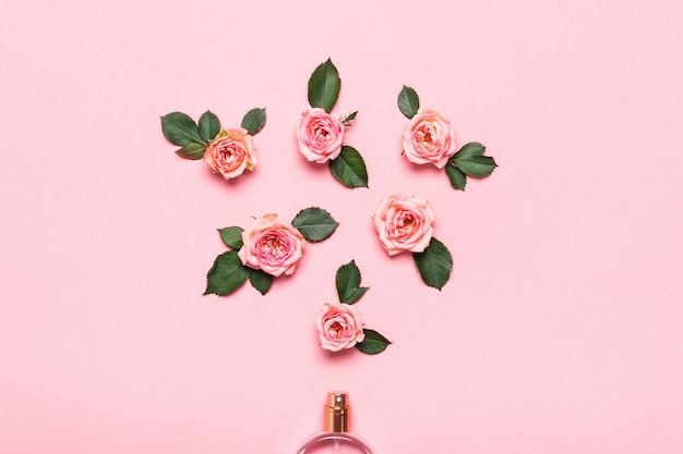 Flasche Parfüm und Rosenblumen auf rosa Hintergrund. Minimales Schönheitskonzept.