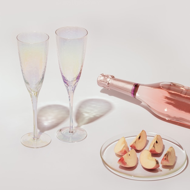 Flasche Rosé-Champagnerwein und leere Gläser Apfelstückchen