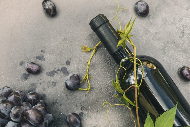 Flasche Rotwein grüne Rebe und reife Traube auf Vintage dunklem Steintisch Hintergrund Draufsicht Kopie sp...