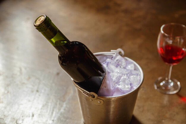 Flasche Rotwein in einem Eiskübel und ein Glas Rotwein