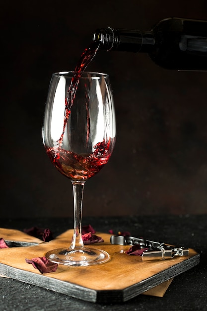 Flasche Rotwein in Glas auf schwarzem Hintergrund gießen