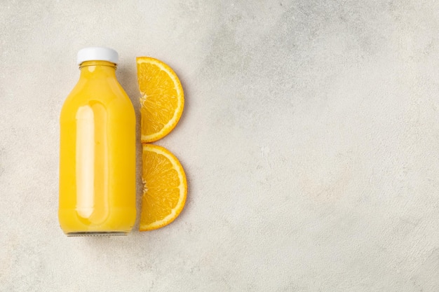 Flasche Saft mit geschnittenen Orangen auf hellem Hintergrund