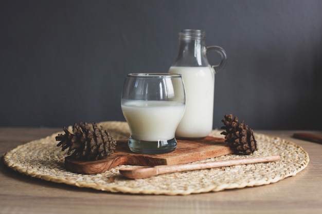 Flasche und Glas leckere Milch auf Holzbrett