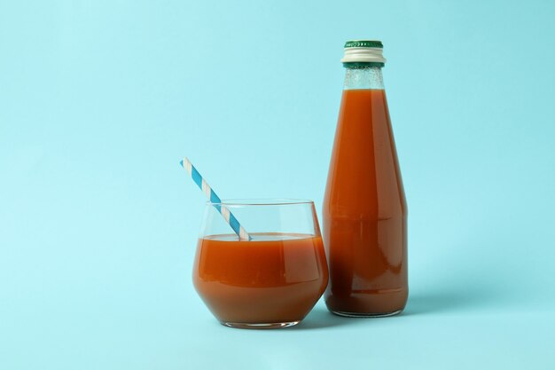 Flasche und Glas Saft auf blauem isoliertem Hintergrund