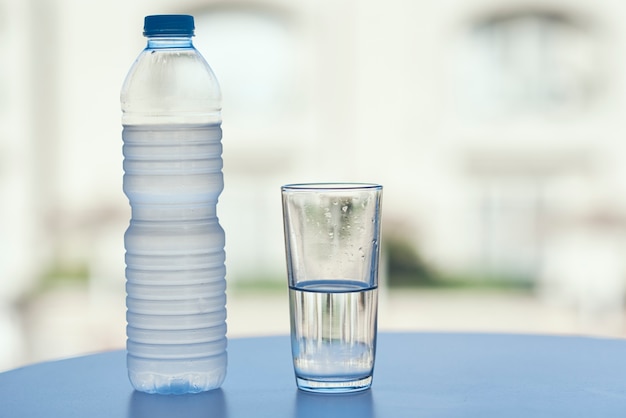 Flasche und Glas Wasser auf dem Tisch