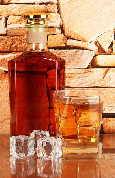 Flasche und Glas Whisky und Eis auf Backsteinmauerhintergrund