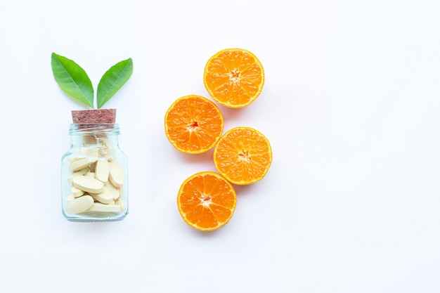 Flasche und Pillen des Vitamins C mit orange Frucht auf Weiß.