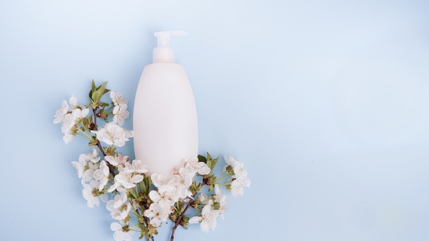 Flasche und weiße Blumen auf blauem Hintergrund.