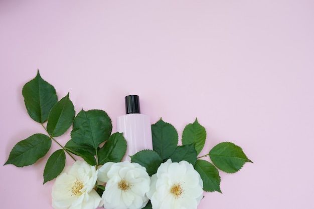 Flasche weibliche Kosmetik mit weißen Blumen auf Rosa