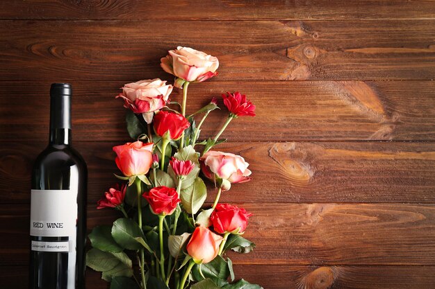 Flasche Wein und Rosen auf einem hölzernen Hintergrund