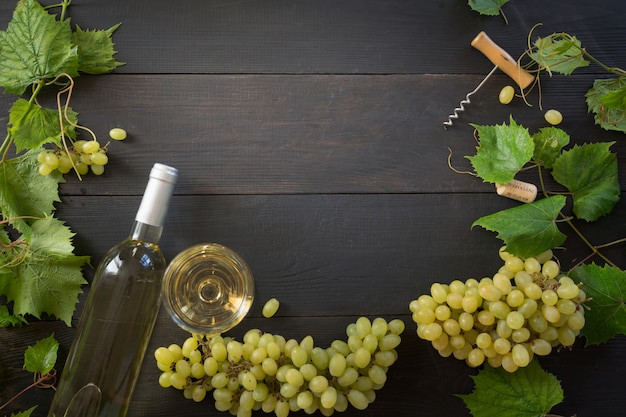 Flasche Weißwein mit Weinglas, Grenze der reifen Traube auf Holztisch