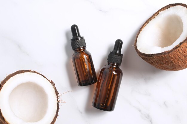 Flaschen Kokosöl und frische Kokosnüsse auf Marmorhintergrund Kokosnuss-Naturkosmetik
