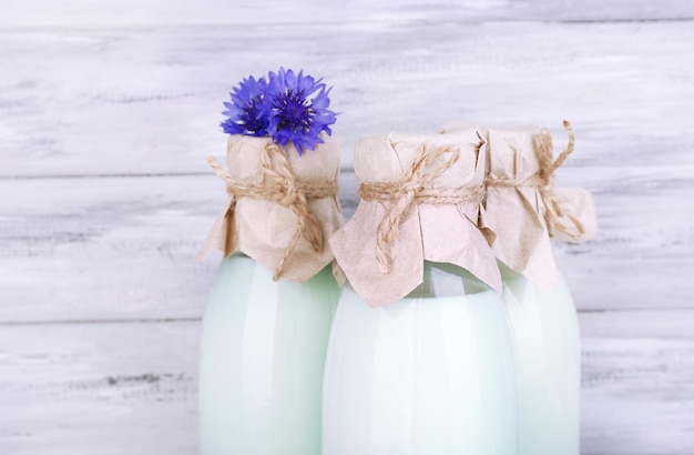Flaschen Milch und Kornblumen auf Holzhintergrund