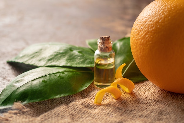 Flaschen mit ätherischem Öl der Orangenschale und Blatt auf Holztisch