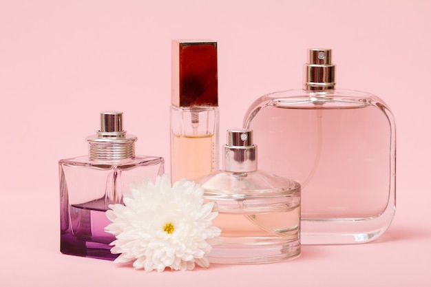 Flaschen mit Frauenparfüm und Blumenknospe in einem rosa Hintergrund. Produkte für Frauen.