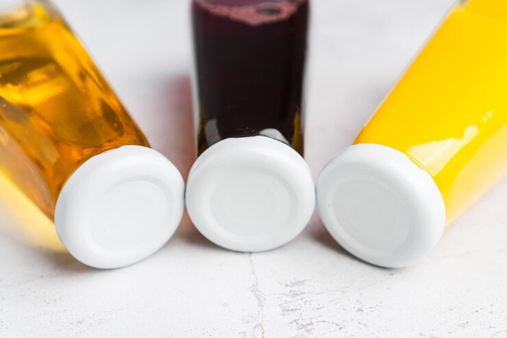 Flaschen mit gelbem und rotem flüssigem halthy-Getränk auf grauem Hintergrund Orangen-Apfel-Kirschsaft