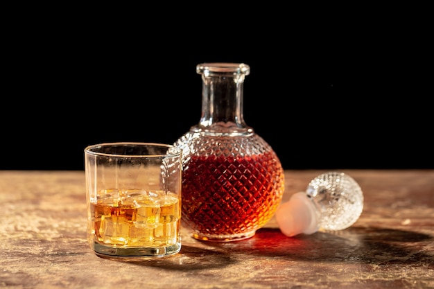 Flaschenwhisky und Glas Whisky mit Eis auf schwarzem Hintergrund