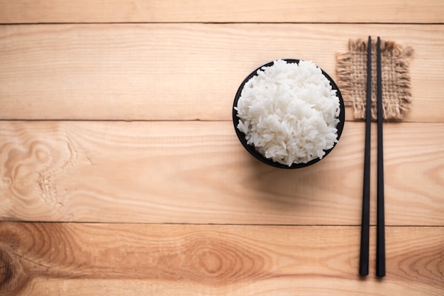 Flast coloque arroz branco em copo preto sobre fundo de madeira. conceito tailandês de alimentos básicos.