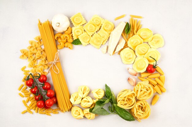 Foto flat lay com diferentes tipos de massa tradicional italiana. penne, tagliatelle, fusilli, farfalle, espaguete e ingredientes para cozinhar. conceito tradicional da culinária italiana. vista do topo