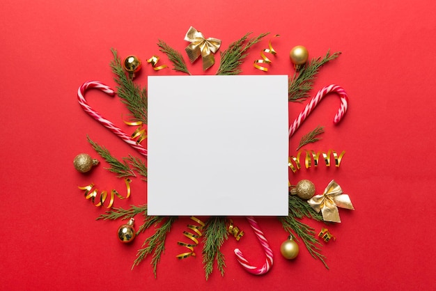 Flat lay Composición de Navidad cuadrado Papel en blanco ramas de pino decoraciones navideñas sobre fondo de color Vista superior espacio de copia para texto