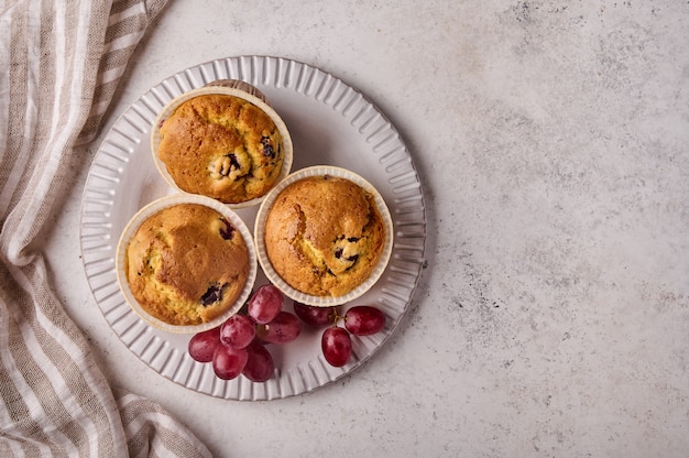 Flat lay cupcakes caseiros com cerejas e uvas no prato com guardanapo na cópia de fundo claro