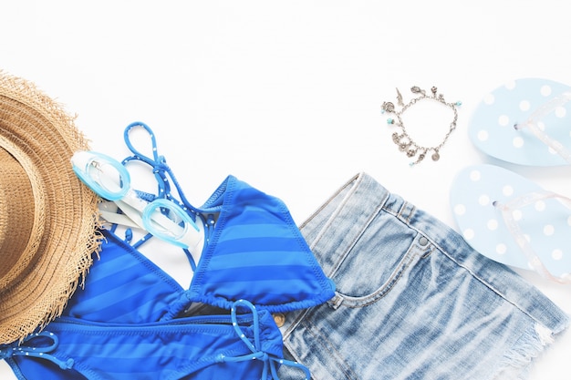 Flat lay do smartphone com biquíni, óculos na cor azul e itens de verão no fundo branco, férias de verão