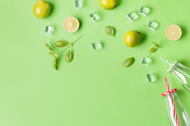 Flat lay con ingredientes para bebidas refrescantes de verano o batidos cubos de hielo hierbas y frascos de vidrio en fondo verde vista superior hielo de fresa limón y albahaca para delicioso cóctel de verano