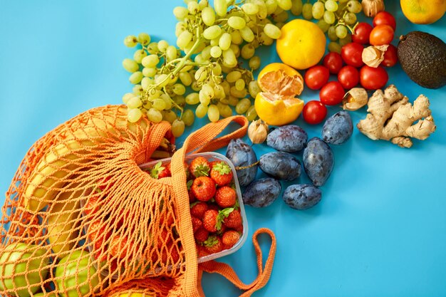 Flat Lay Mesh Lebensmitteleinkauf umweltfreundliche Tasche mit Früchten auf blauem Leinwandhintergrund Zero Waste cconcept Lokaler Bauernmarkt Einkaufszentrum Draufsicht Kopierbereich Kunststofffreie Artikel