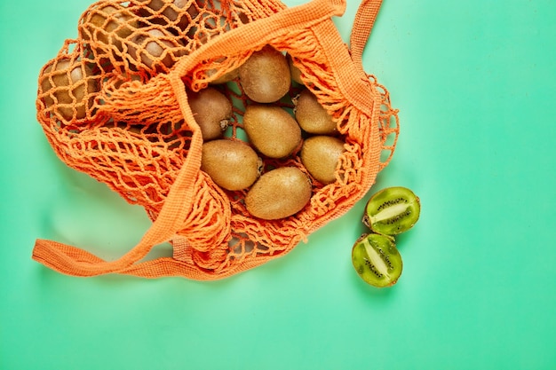 Flat Lay Mesh Lebensmitteleinkauf umweltfreundliche Tasche mit Kiwi auf grünem Leinwandhintergrund Zero Waste cconcept Lokaler Bauernmarkt Einkaufszentrum Draufsicht Kopierbereich Kunststofffreie Artikel
