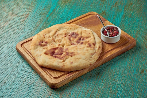 Flatbread de pan turco clásico servido en una tabla de madera sobre una mesa verde. Pan turco